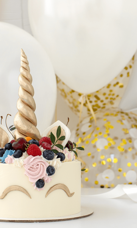 A cake with gold frosting and fruit on top.